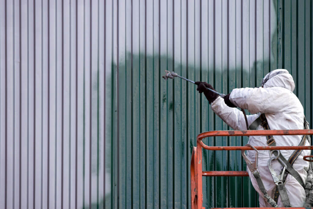 Commercial painter applying fresh paint to modern office building exterior in Ocala