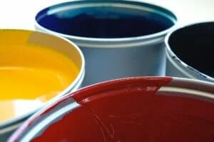 Four paint cans filled with bright primary colors: yellow, blue, and red, viewed from the top on a plain background, ready for a professional painter in central Florida.